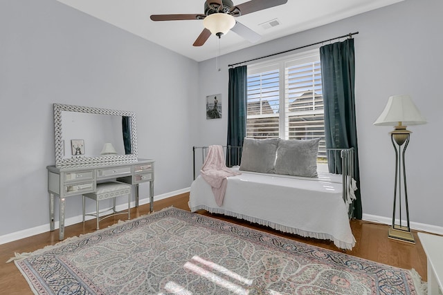 bedroom with wood finished floors, visible vents, baseboards, and ceiling fan