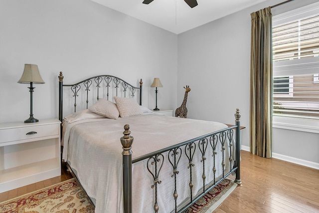 bedroom with light wood finished floors, a ceiling fan, and baseboards