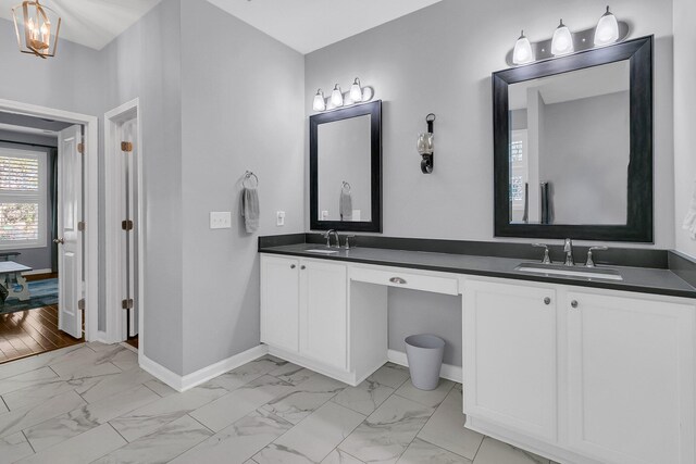 full bathroom with marble finish floor, baseboards, a sink, and double vanity
