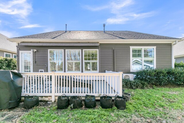 rear view of property with a wooden deck and a shingled roof