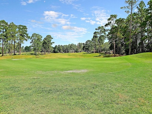 view of home's community with view of golf course and a yard