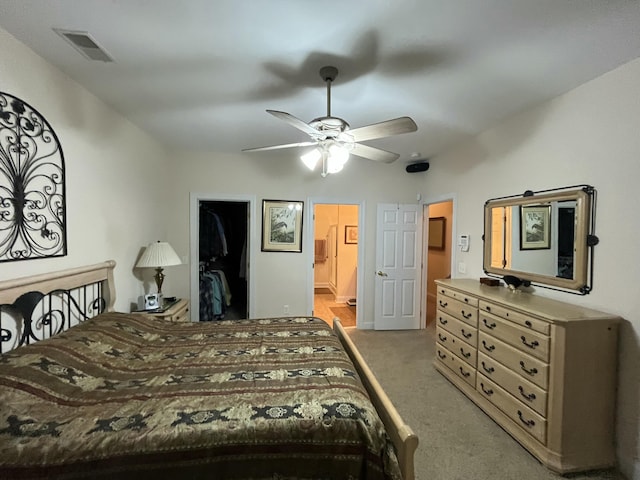 bedroom with a walk in closet, ceiling fan, connected bathroom, light colored carpet, and a closet