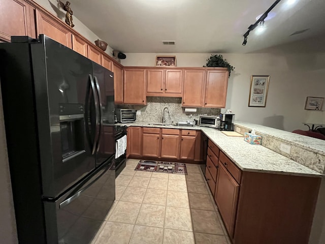 kitchen featuring sink, kitchen peninsula, decorative backsplash, light tile patterned flooring, and black appliances