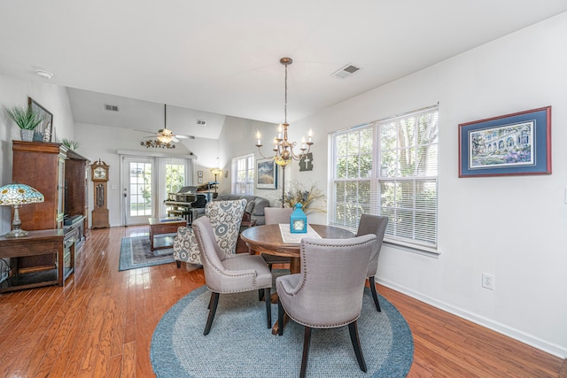 dining room featuring lofted ceiling, wood-type flooring, ceiling fan with notable chandelier, and french doors