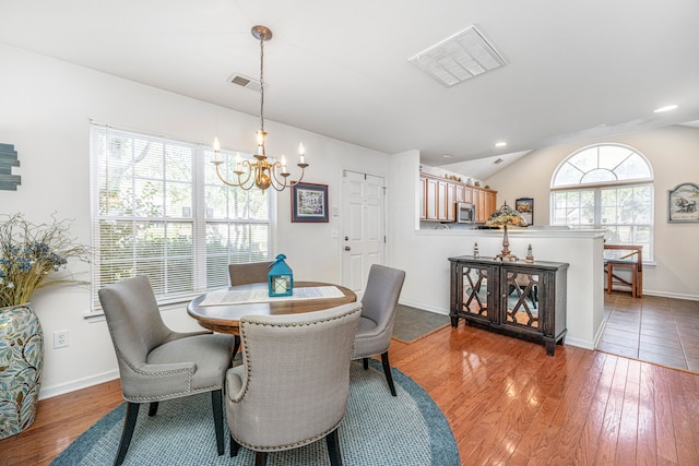 dining room featuring vaulted ceiling, light hardwood / wood-style flooring, and a chandelier