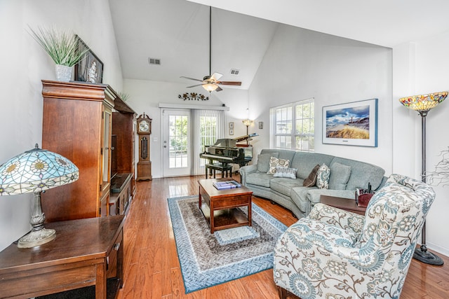 living room featuring high vaulted ceiling, a healthy amount of sunlight, ceiling fan, and light hardwood / wood-style flooring