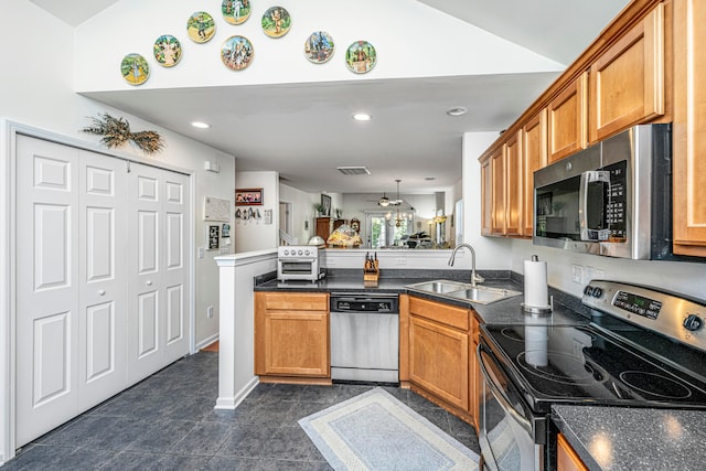 kitchen featuring stainless steel appliances, dark tile patterned flooring, sink, kitchen peninsula, and pendant lighting