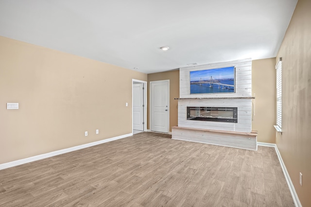 unfurnished living room with a large fireplace and light hardwood / wood-style flooring