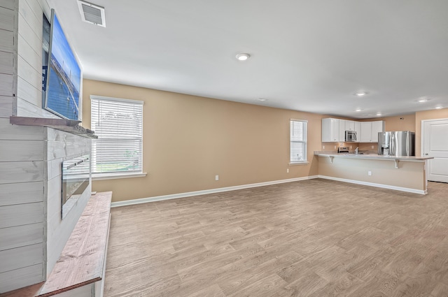 unfurnished living room with light wood-type flooring and a fireplace