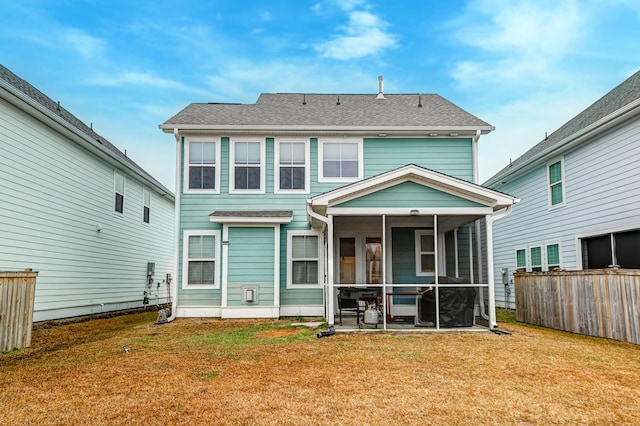 rear view of house with a sunroom, fence, a lawn, and roof with shingles