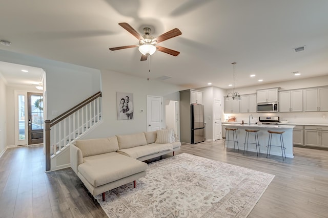 living room with recessed lighting, visible vents, stairway, and light wood finished floors