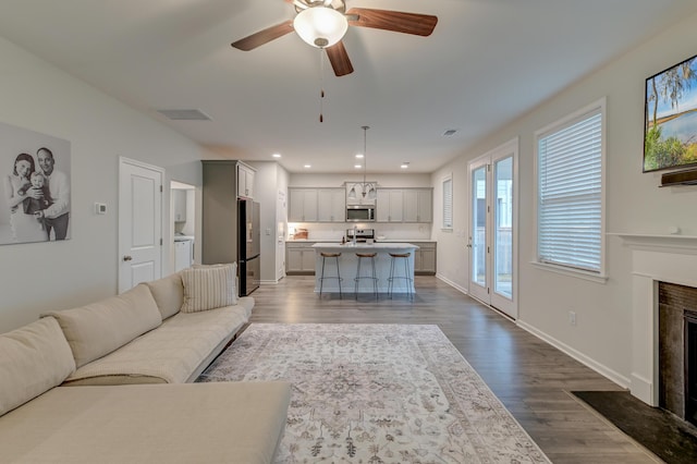 living area featuring visible vents, baseboards, dark wood-style floors, a fireplace with flush hearth, and recessed lighting