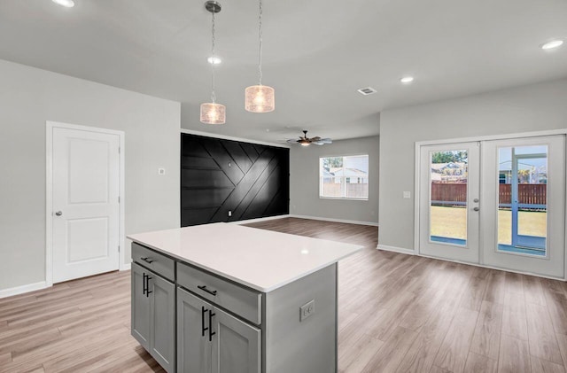 kitchen with pendant lighting, ceiling fan, a barn door, light hardwood / wood-style floors, and a kitchen island