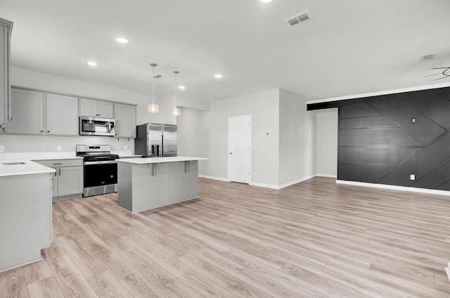 kitchen featuring gray cabinets, pendant lighting, light wood-type flooring, and appliances with stainless steel finishes