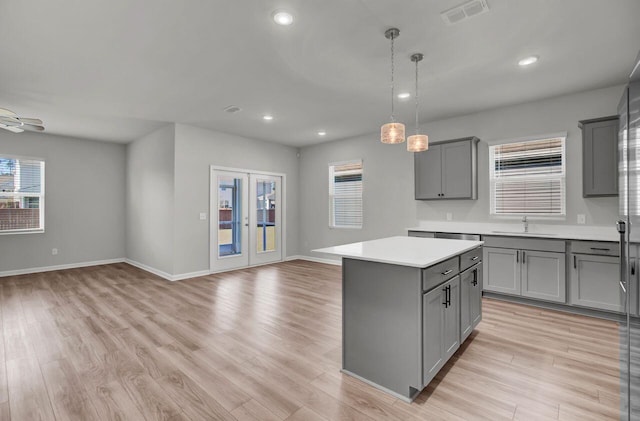 kitchen featuring gray cabinetry, hanging light fixtures, ceiling fan, light hardwood / wood-style floors, and a kitchen island