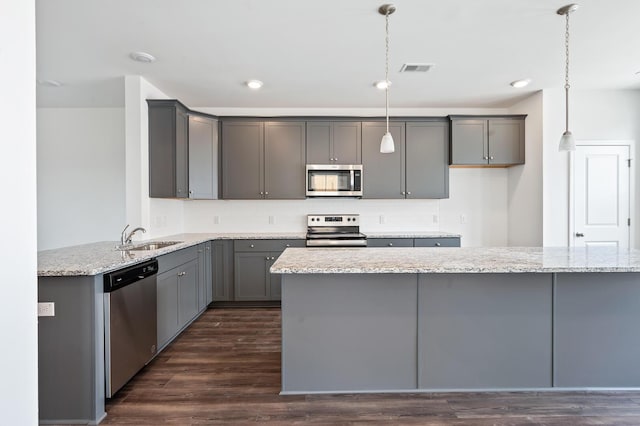 kitchen featuring sink, gray cabinets, decorative light fixtures, light stone counters, and stainless steel appliances