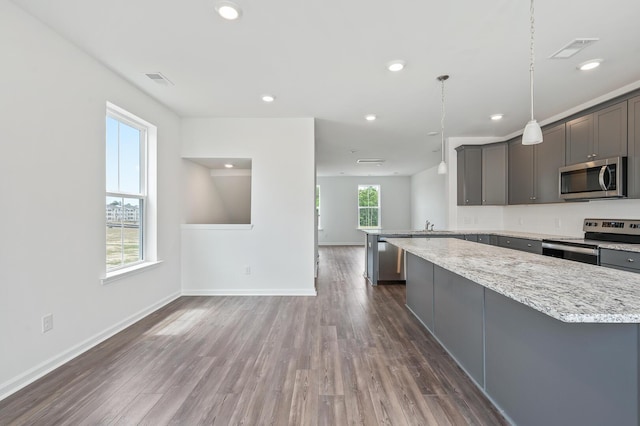 kitchen featuring light stone counters, dark hardwood / wood-style flooring, stainless steel appliances, and decorative light fixtures