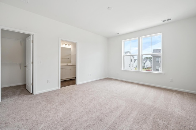 unfurnished bedroom with carpet flooring, connected bathroom, a spacious closet, and a closet