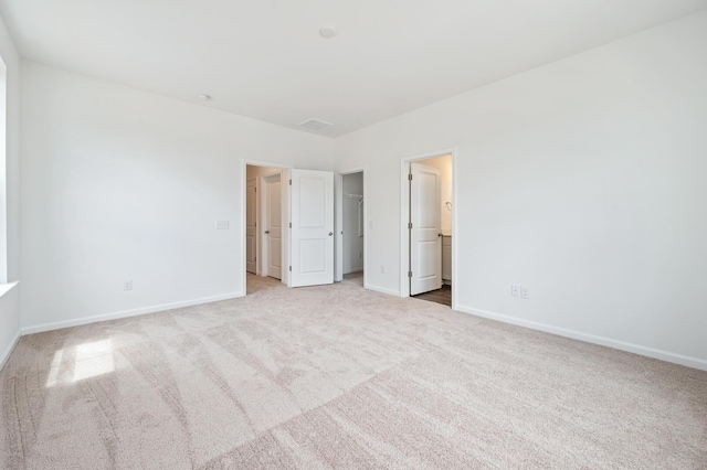 unfurnished bedroom featuring connected bathroom and light colored carpet