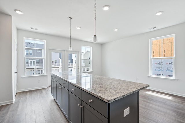 kitchen featuring light hardwood / wood-style floors, a center island, a healthy amount of sunlight, and hanging light fixtures