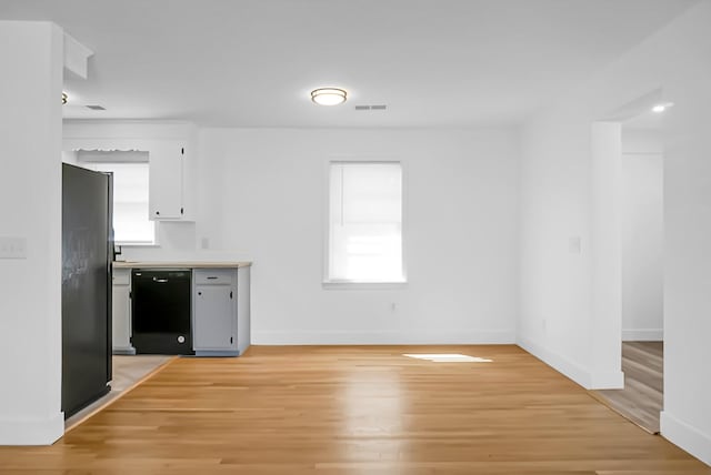 interior space with white cabinetry, light hardwood / wood-style floors, and black appliances