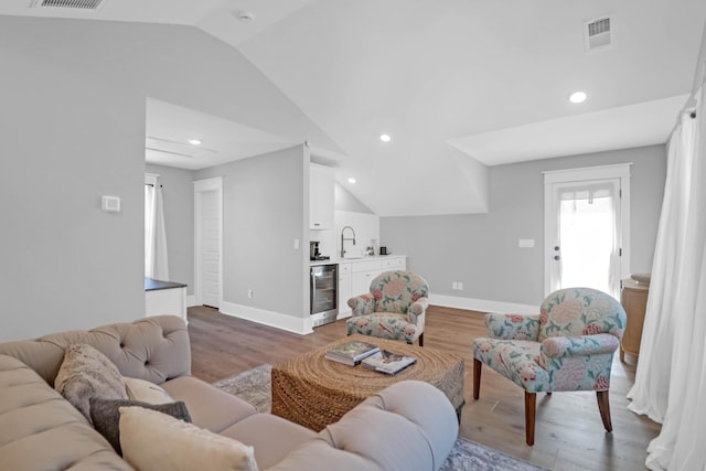 living room with hardwood / wood-style flooring, vaulted ceiling, wet bar, and beverage cooler