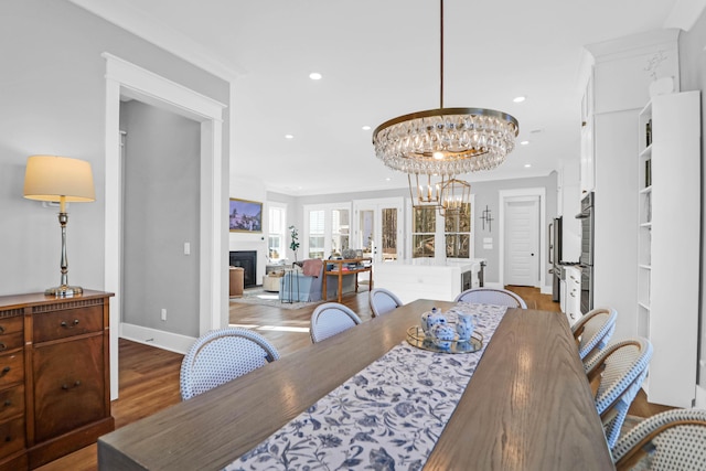 dining space featuring an inviting chandelier, hardwood / wood-style flooring, ornamental molding, and french doors