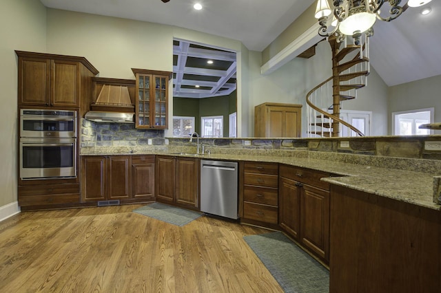 kitchen featuring coffered ceiling, stainless steel appliances, a sink, light wood finished floors, and visible vents