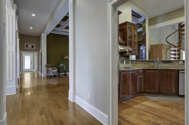 corridor featuring stairs, baseboards, a sink, light wood finished floors, and visible vents