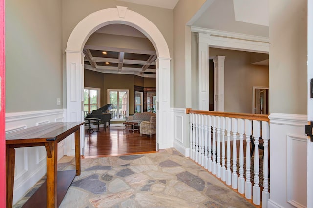 corridor with coffered ceiling, hardwood / wood-style flooring, beam ceiling, and ornate columns