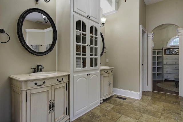 bathroom featuring baseboards, visible vents, a sink, and two vanities
