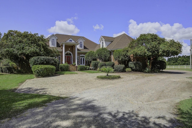 view of front of home featuring fence, brick siding, and curved driveway