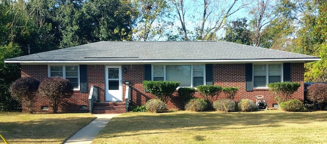 view of front of house featuring entry steps, a shingled roof, a front lawn, and brick siding