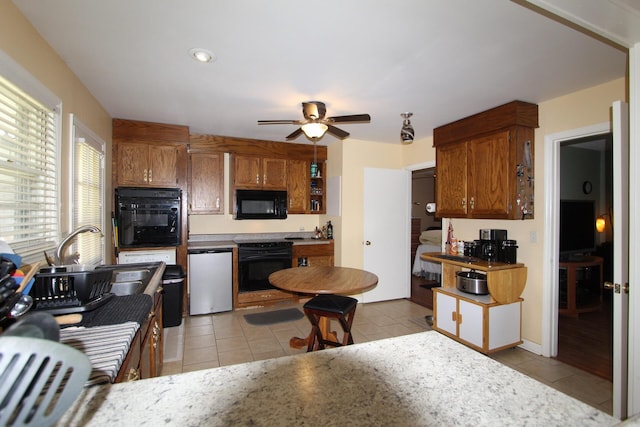 kitchen with brown cabinetry, black appliances, and light tile patterned floors