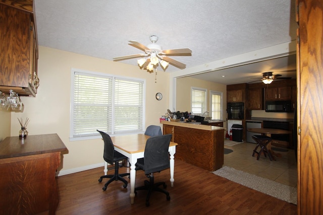 dining area featuring a ceiling fan, a textured ceiling, baseboards, and wood finished floors