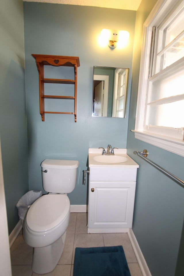 half bathroom with toilet, vanity, baseboards, and tile patterned floors