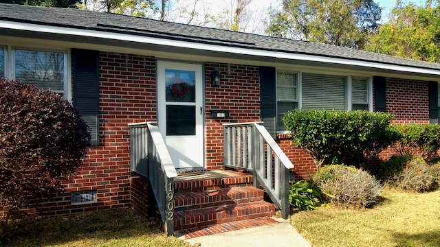 view of front of property featuring crawl space, a shingled roof, and brick siding