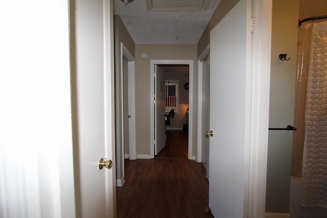 hallway featuring attic access and dark wood finished floors