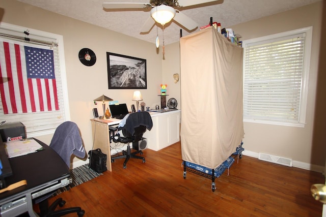 office area featuring visible vents, a ceiling fan, a textured ceiling, wood finished floors, and baseboards