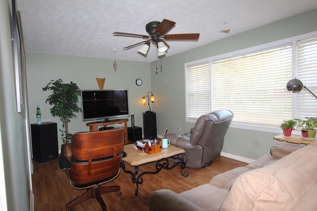 living area featuring a textured ceiling, ceiling fan, wood finished floors, and baseboards