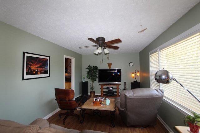 living area featuring ceiling fan, a textured ceiling, baseboards, and wood finished floors