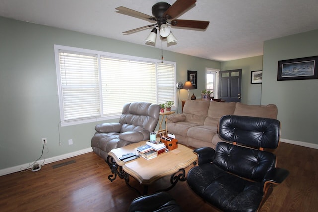 living room featuring a ceiling fan, visible vents, baseboards, and wood finished floors