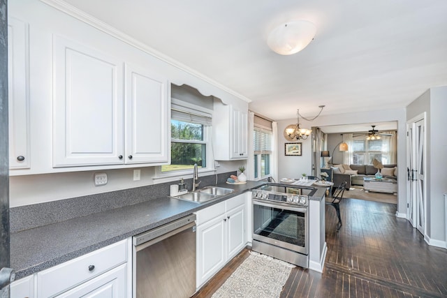 kitchen featuring stainless steel appliances, dark countertops, a sink, and white cabinets