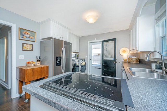 kitchen with dark wood-style flooring, stainless steel appliances, white cabinetry, separate washer and dryer, and a sink