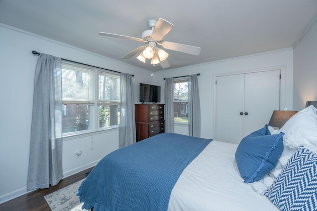 bedroom with crown molding, a closet, dark wood-type flooring, a ceiling fan, and baseboards