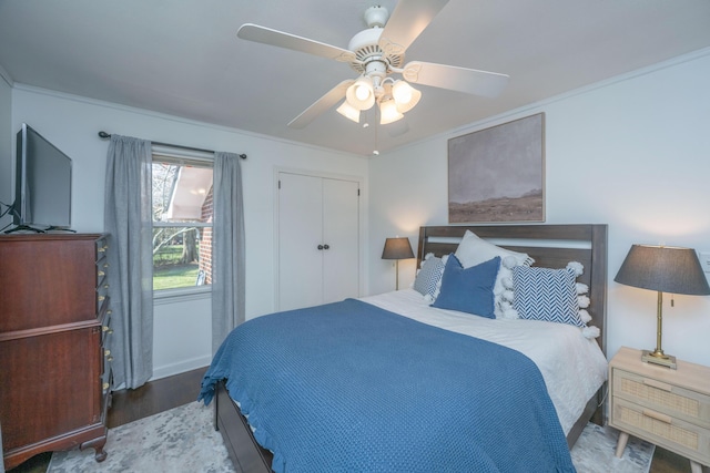 bedroom featuring ceiling fan, a closet, crown molding, and wood finished floors