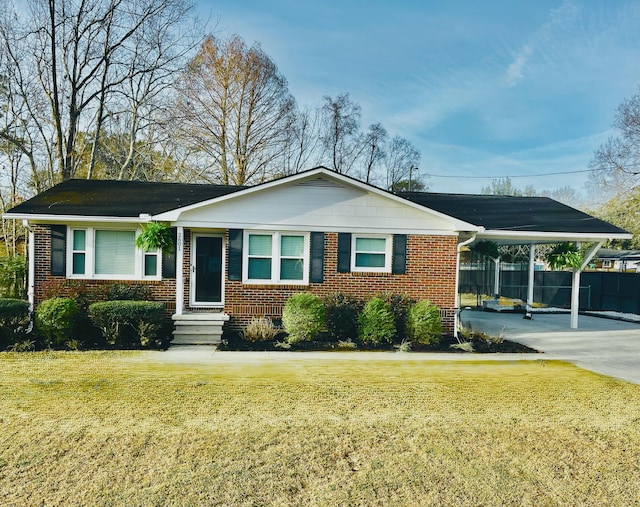 view of front of house with a carport, a front lawn, concrete driveway, and brick siding