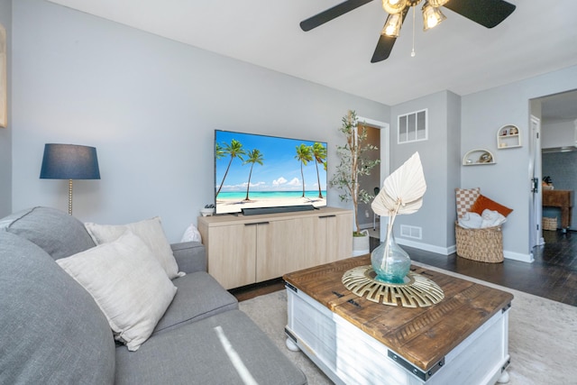 living room with baseboards, visible vents, and wood finished floors