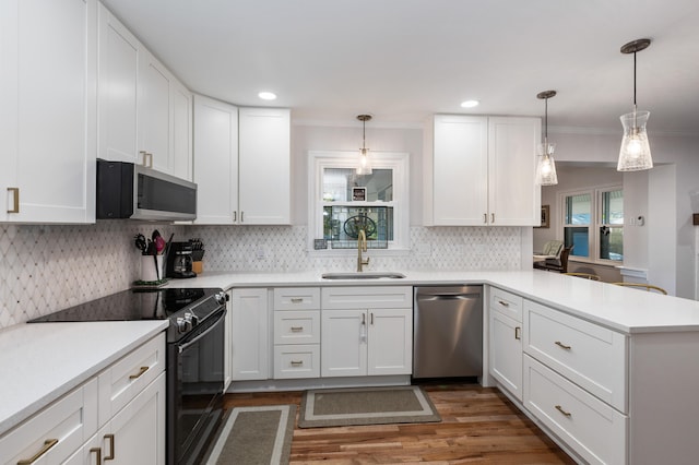 kitchen with appliances with stainless steel finishes, sink, decorative light fixtures, and white cabinets