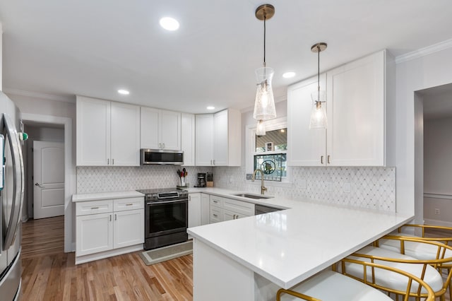 kitchen featuring kitchen peninsula, white cabinets, a breakfast bar, sink, and stainless steel appliances